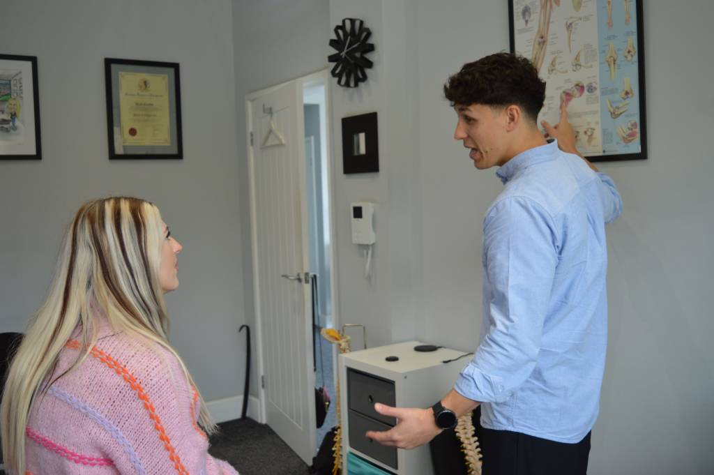 Man pointing at poster explaining to woman sat down